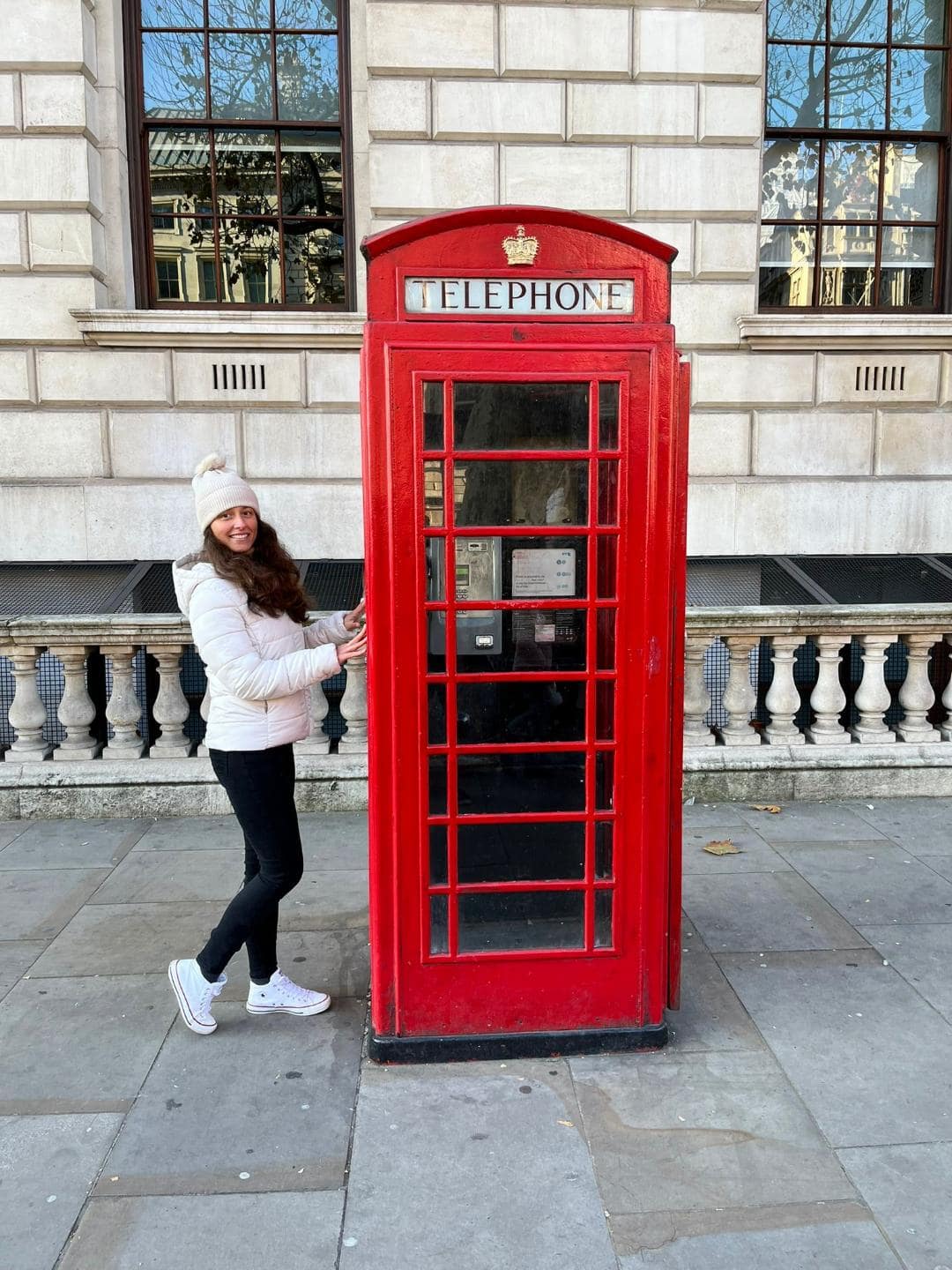 Dievča pri typickej londýnskej červenej telefónnej búdke.