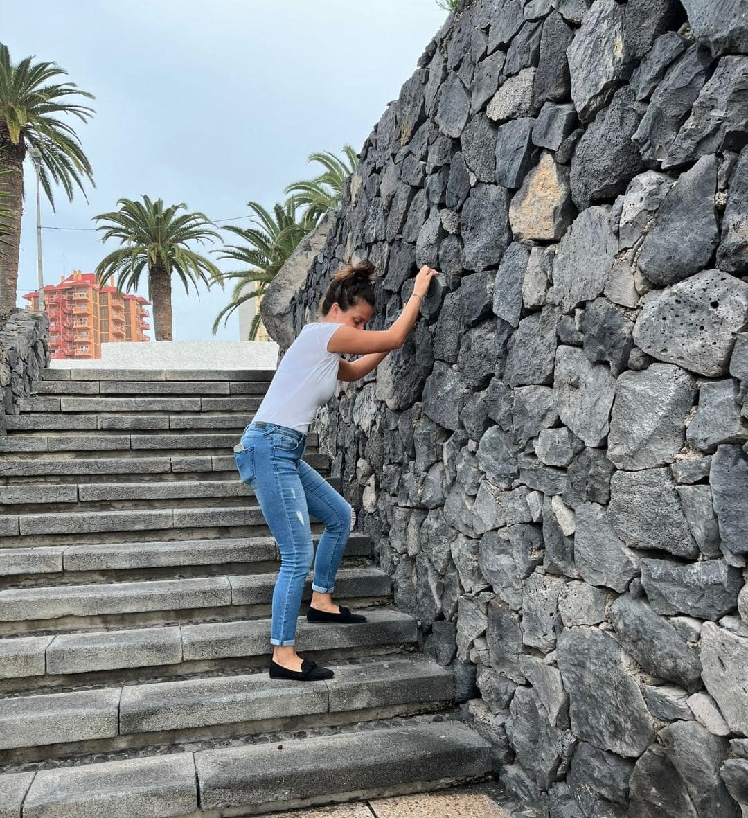 Dievča kráčajúce po schodoch s drží kamennej steny.