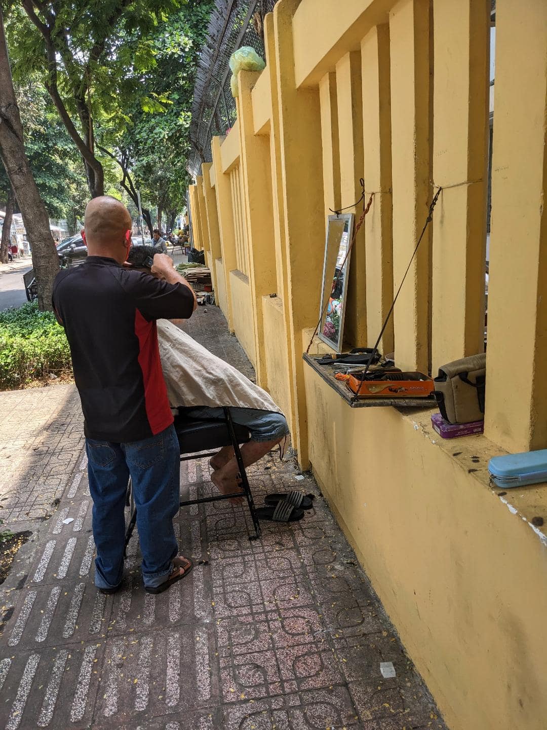 Barber v ulici Ho Chi Minh strihá chlapa.