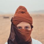 Žena na púšti zahalená v šatke.
