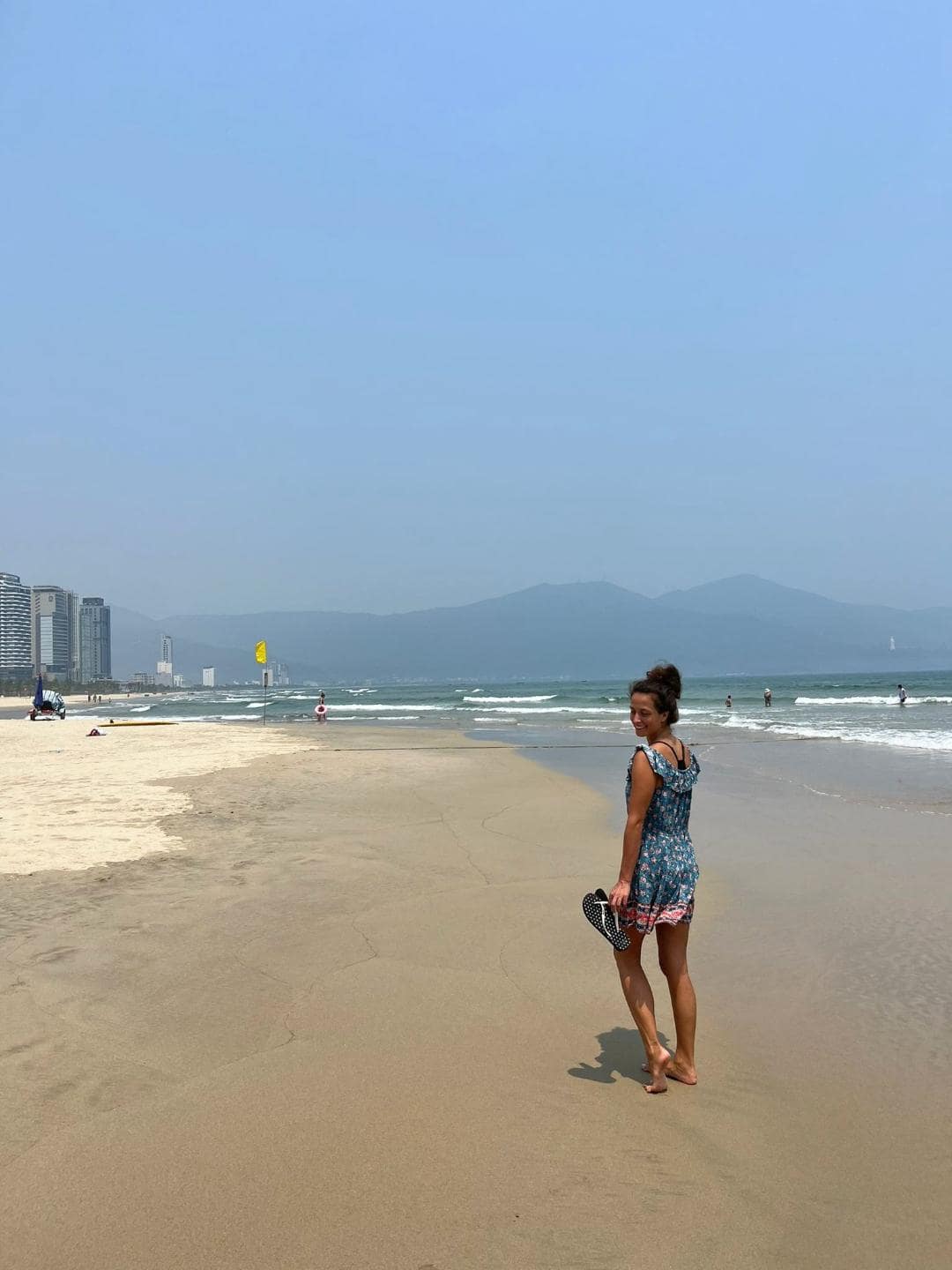 Dievča v modrých šatách kráča po pláži v meste Da Nang.
