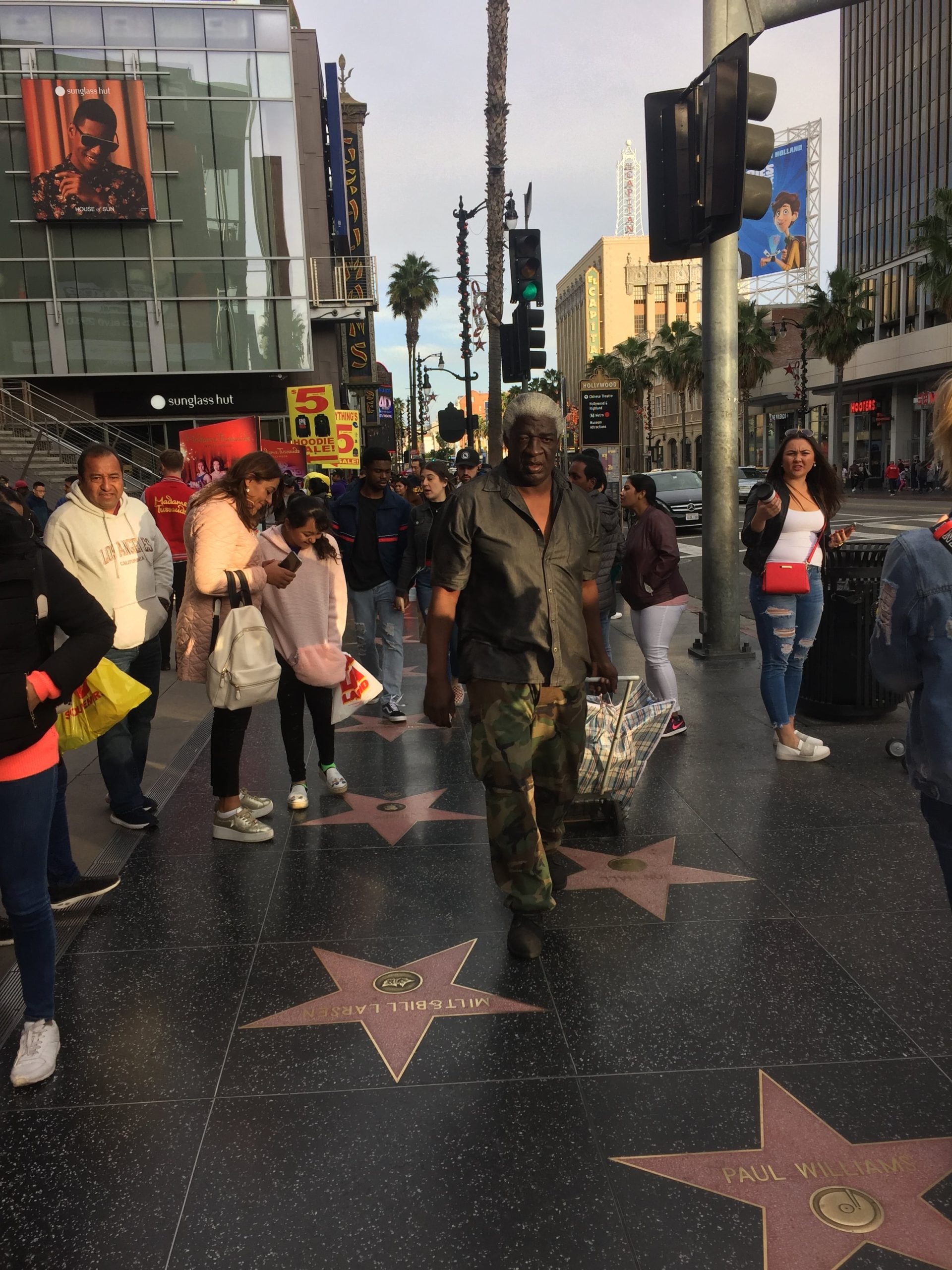 Bezdomovec uprostred turistov na chodníku Walk of Fame.