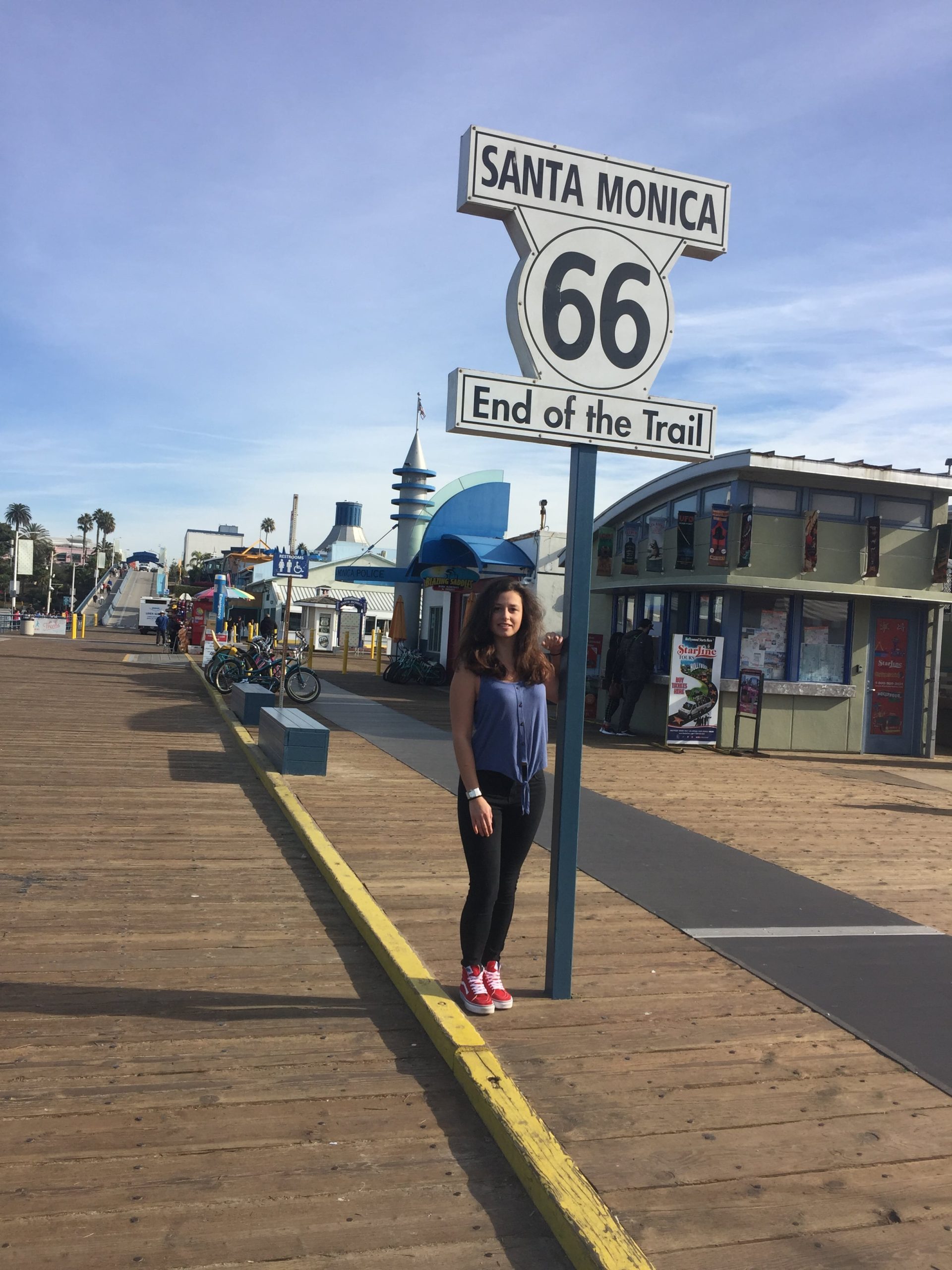 Dievča stojí na móle pri nápise Route 66. Je to miesto, kde končí najdlhšia diaľnica v USA.