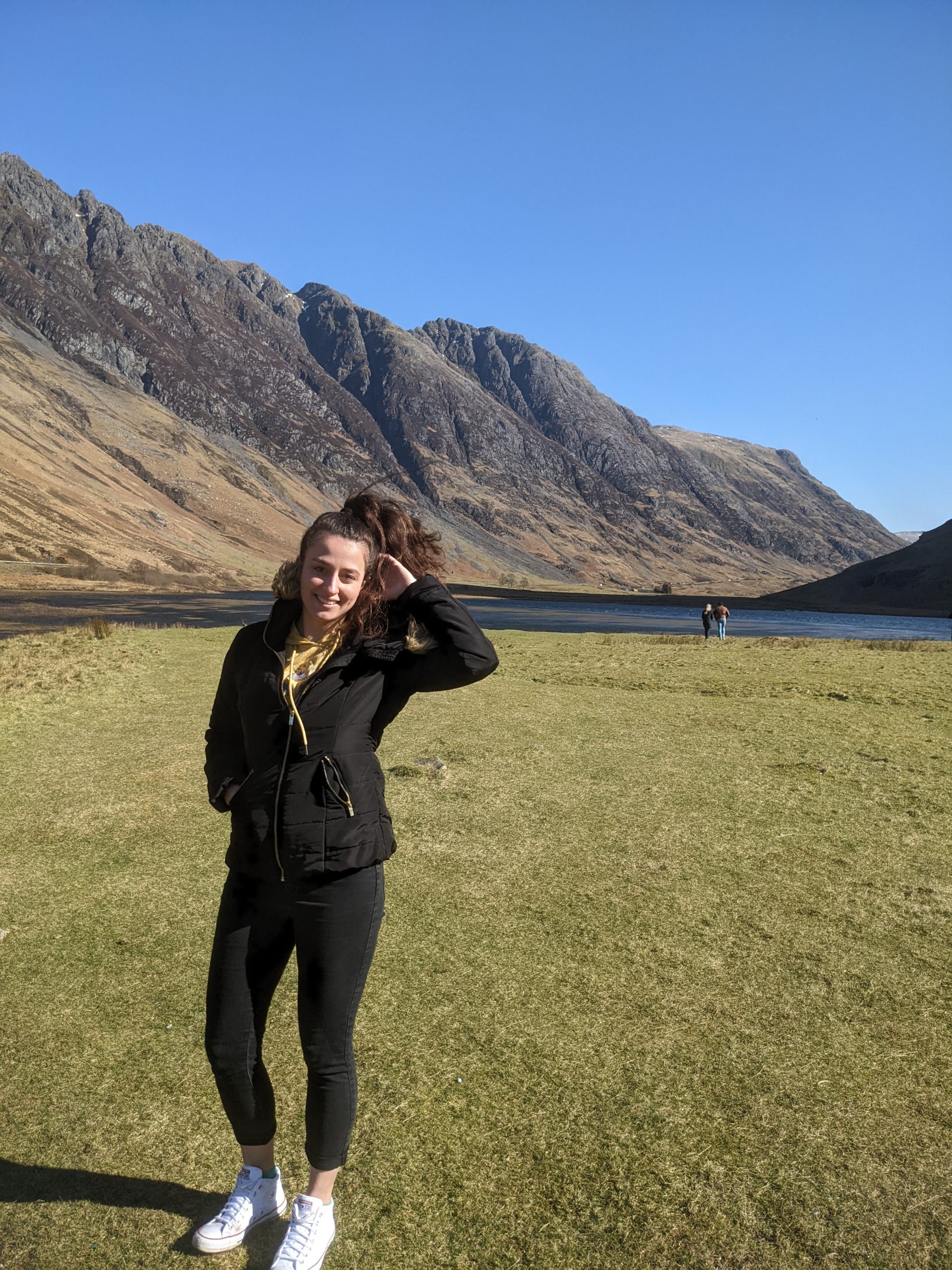 Dievča v škótskej vysočine. Za ňou je krásna príroda, jazero a kopce.