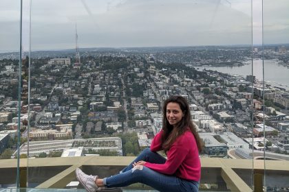 Výhľad na mesto Seattle z vyhliadkovej veži Space Needle. Dievča v rúžovom svetríku pózuje na lavičke.