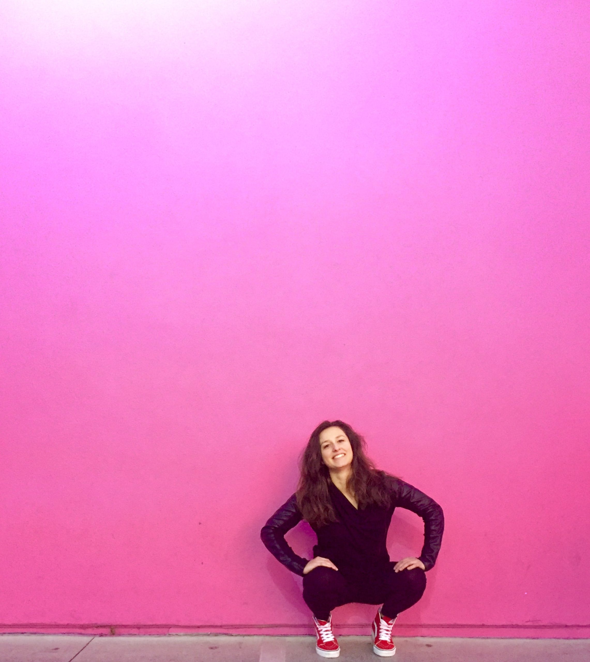 Dievča čupí pred rúžovou stenou.