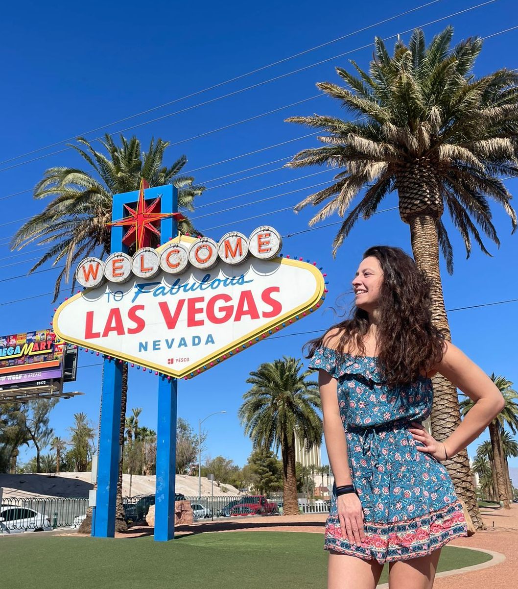 Dievča v minišatách pózuje pred tabuľou Welcome to Las Vegas.