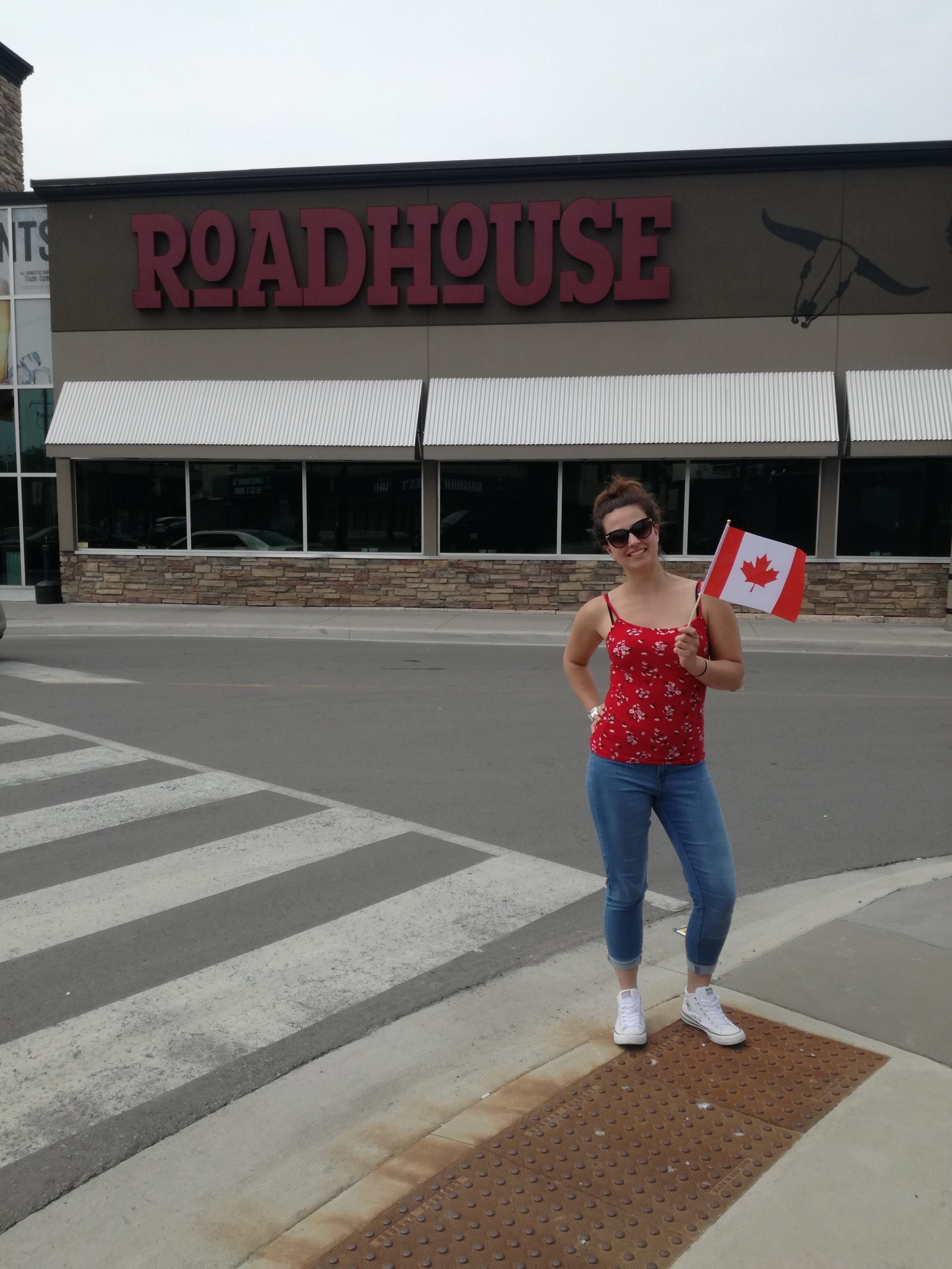 Dievča s kanadskou vlajkou stojí pred reštauráciou.