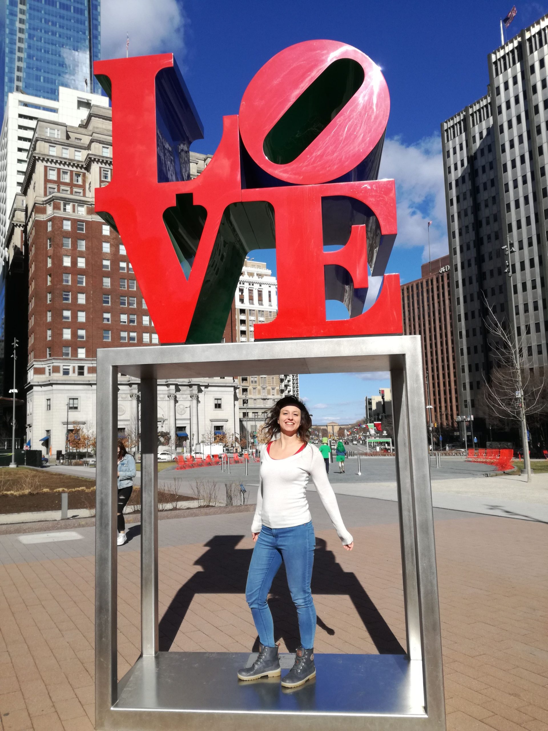 Dievča stojí na námestí pod symbolom LOVE.