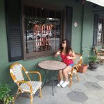 Dievča v červenom tričku sedí na terase reštaurácie.