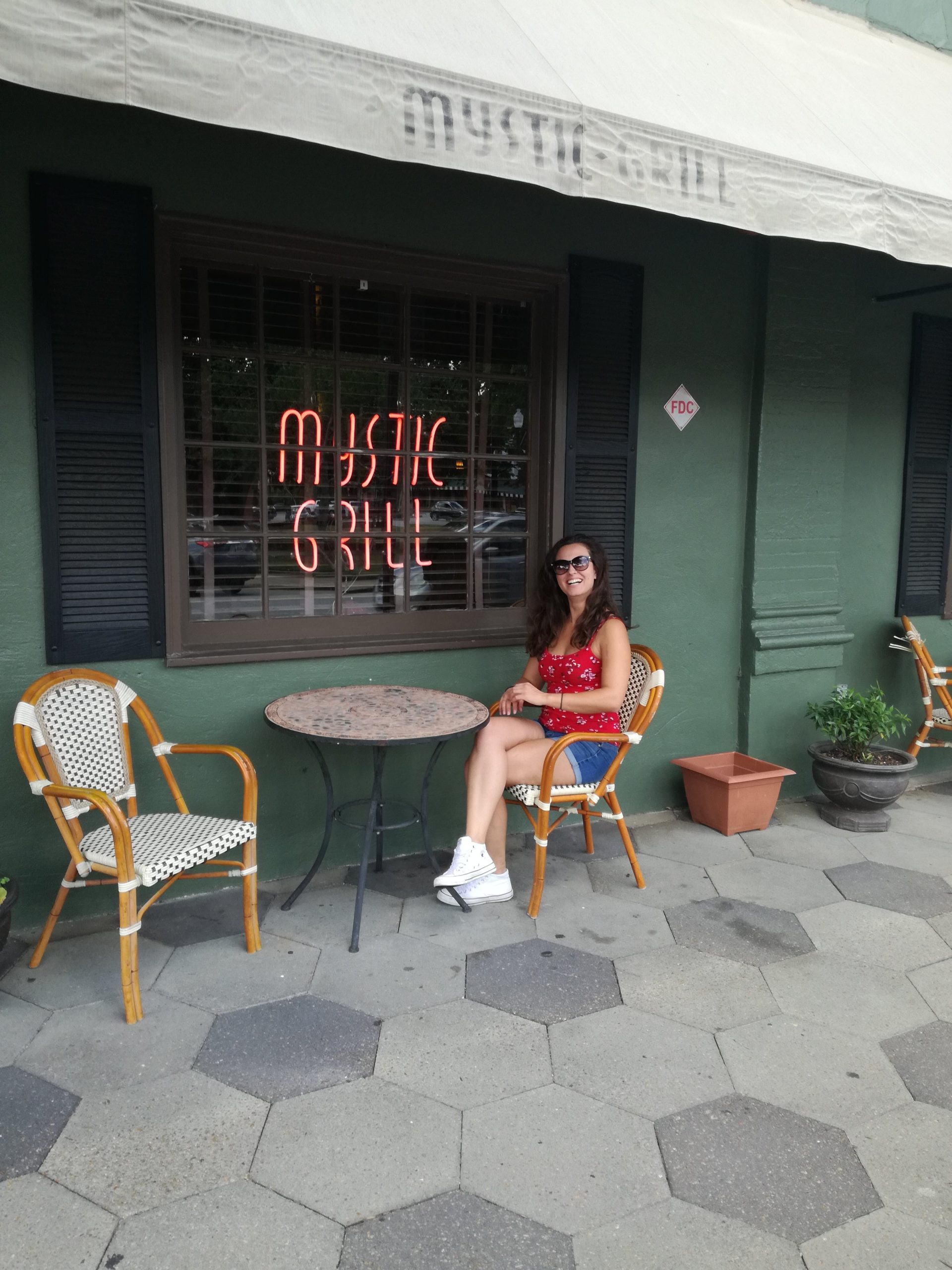 Dievča sedí na stoličke na terase reštaurácie Mystic Grill.