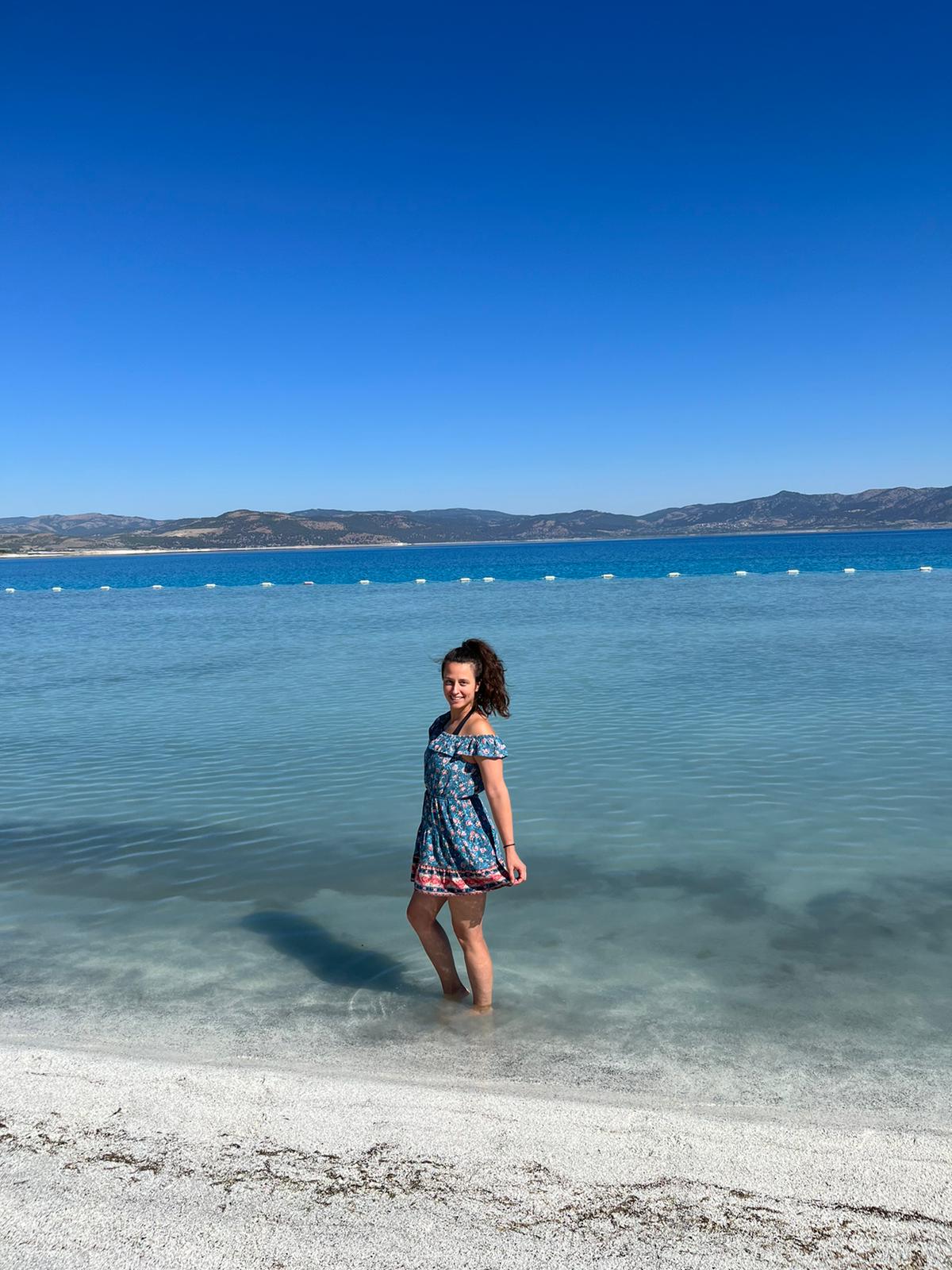 Dievča stojí v priezračne modrom jazere a pózuje.