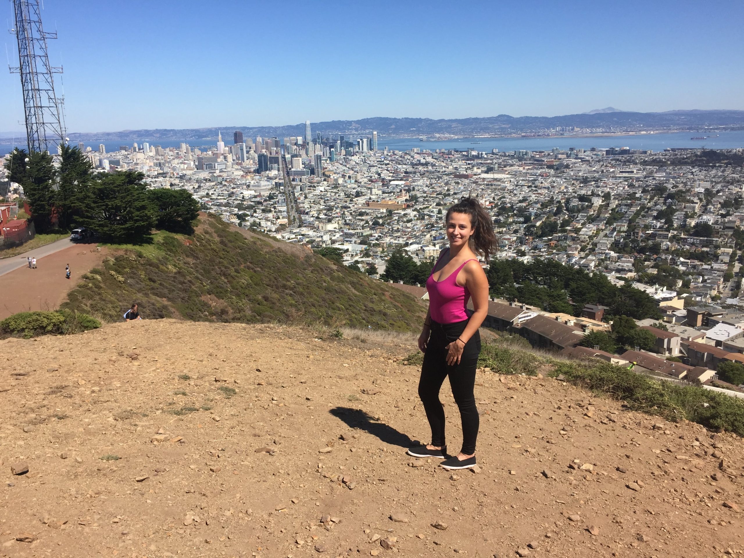 Dievča stojí na kopci. Za ňou je mesto San Francisco.