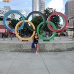 Dievča v čiernom tričku stojí pred olympijskými kruhmi v Atlante.