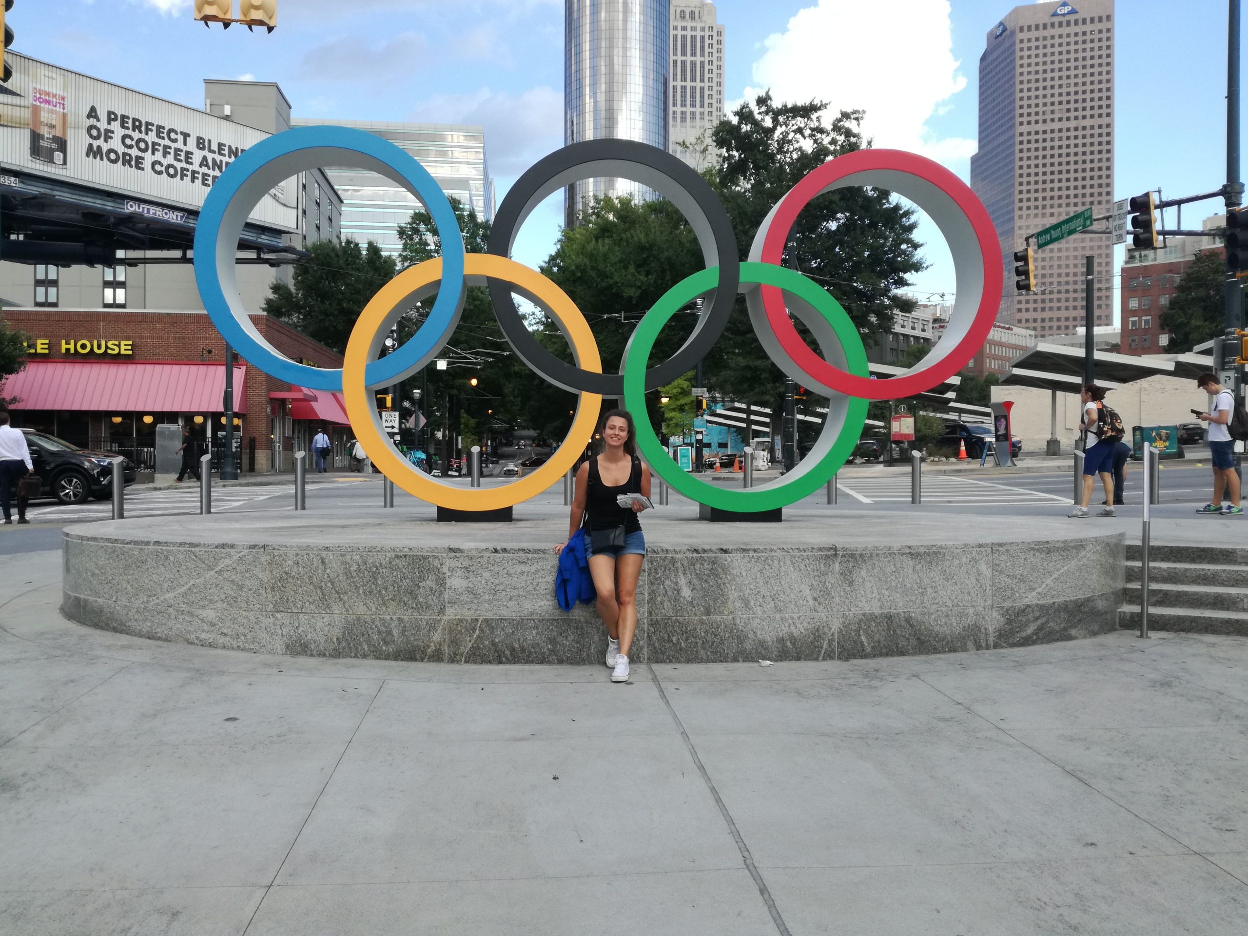 Dievča v čiernom tričku stojí pred olympijskými kruhmi v Atlante.