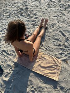 Dievča v plavkách sedí na pláži na osuške.