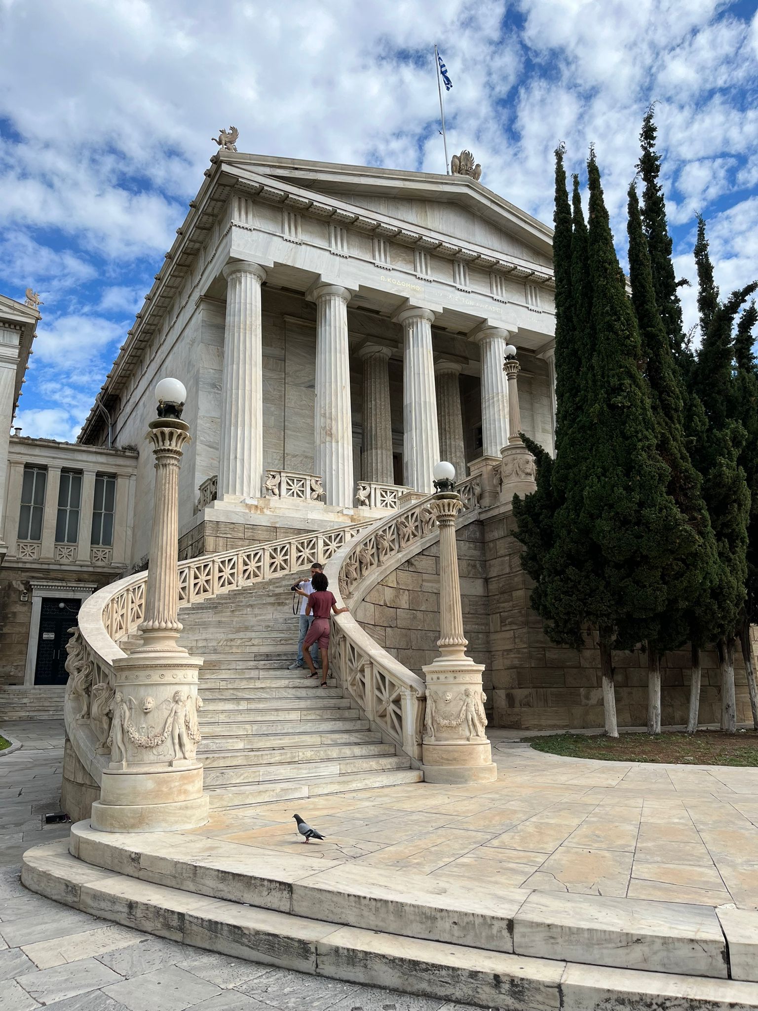 Historická budova knižnice v Aténach. Je biela a má nádherné točité schodisko.