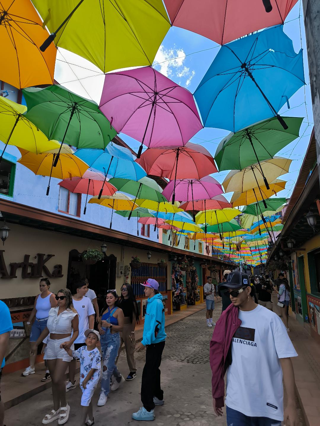 Ulica plná turistov. Nad ich hlavami visia dáždniky.