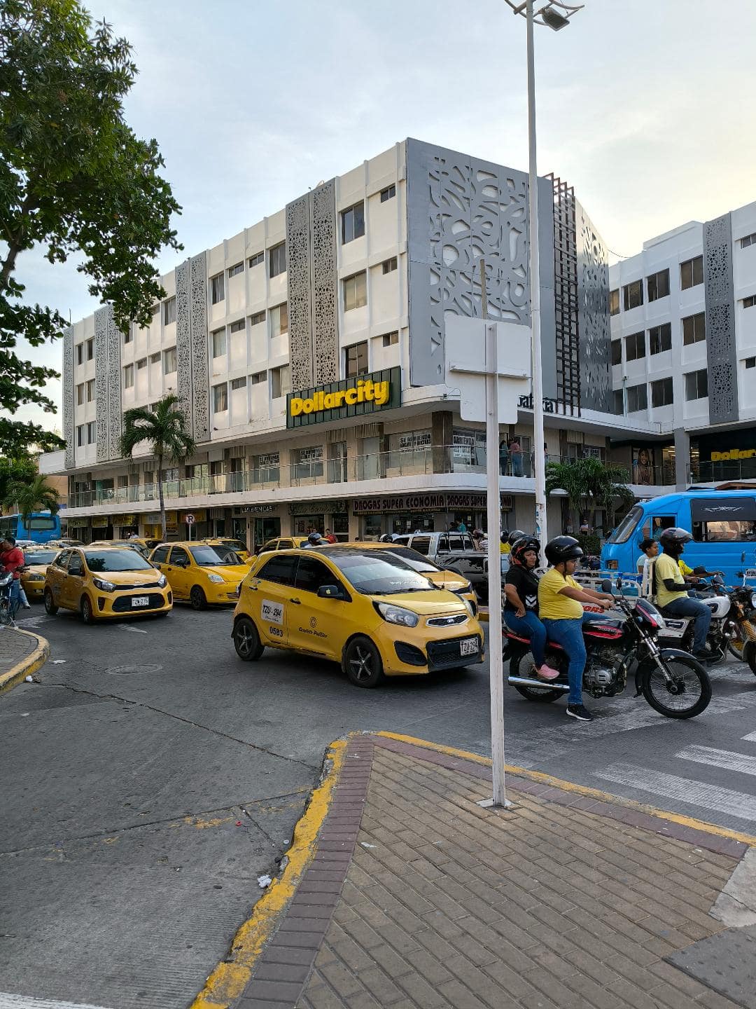 Žlté taxíky, modrý autobus a cyklista stoja na križovatke.