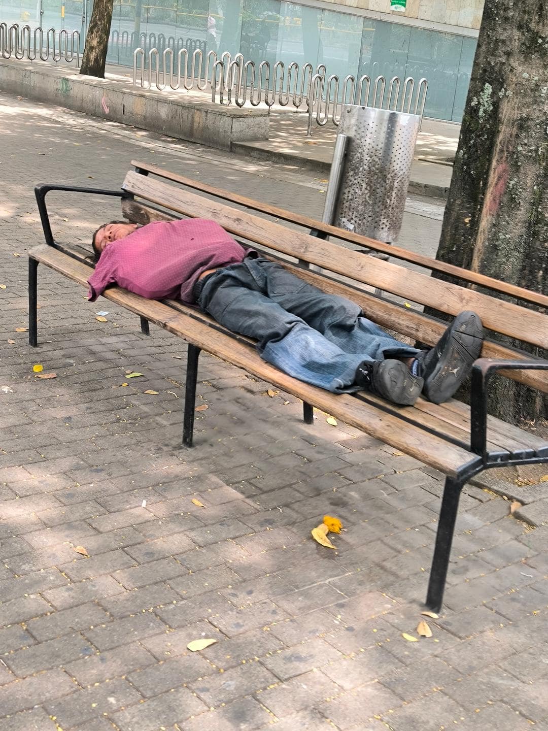 Bezdomovec spiaci na lavičke.