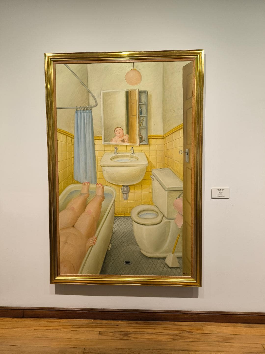 Obraz, na ktorom je muž so ženou v kúpeľni. Žena sa kúpe a muž sa obzerá v zrkadle.