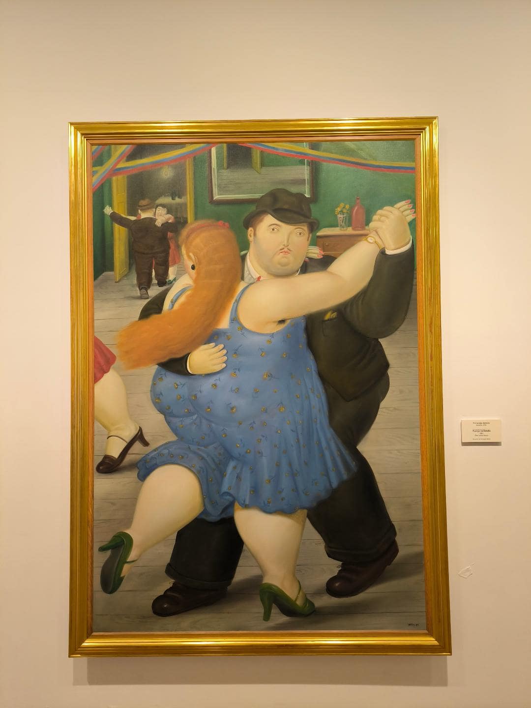 Na obraze tancuje muž v čiernom smokingu so ženou v modrých šatách.
