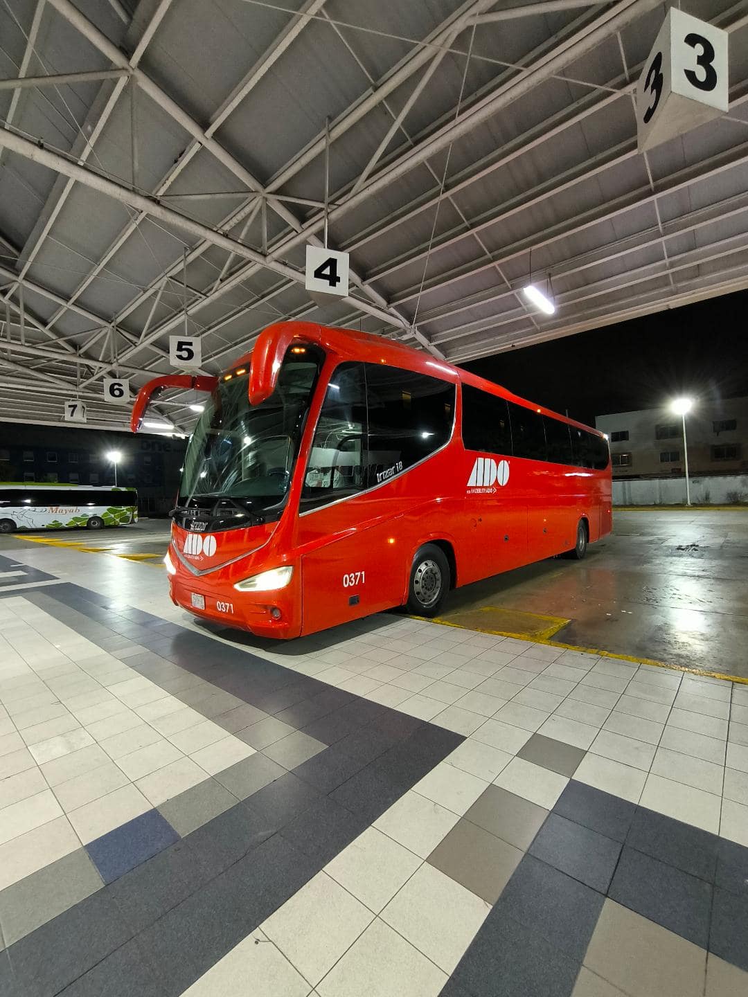 Červený autobus stojí v noci na autobusovej stanici.
