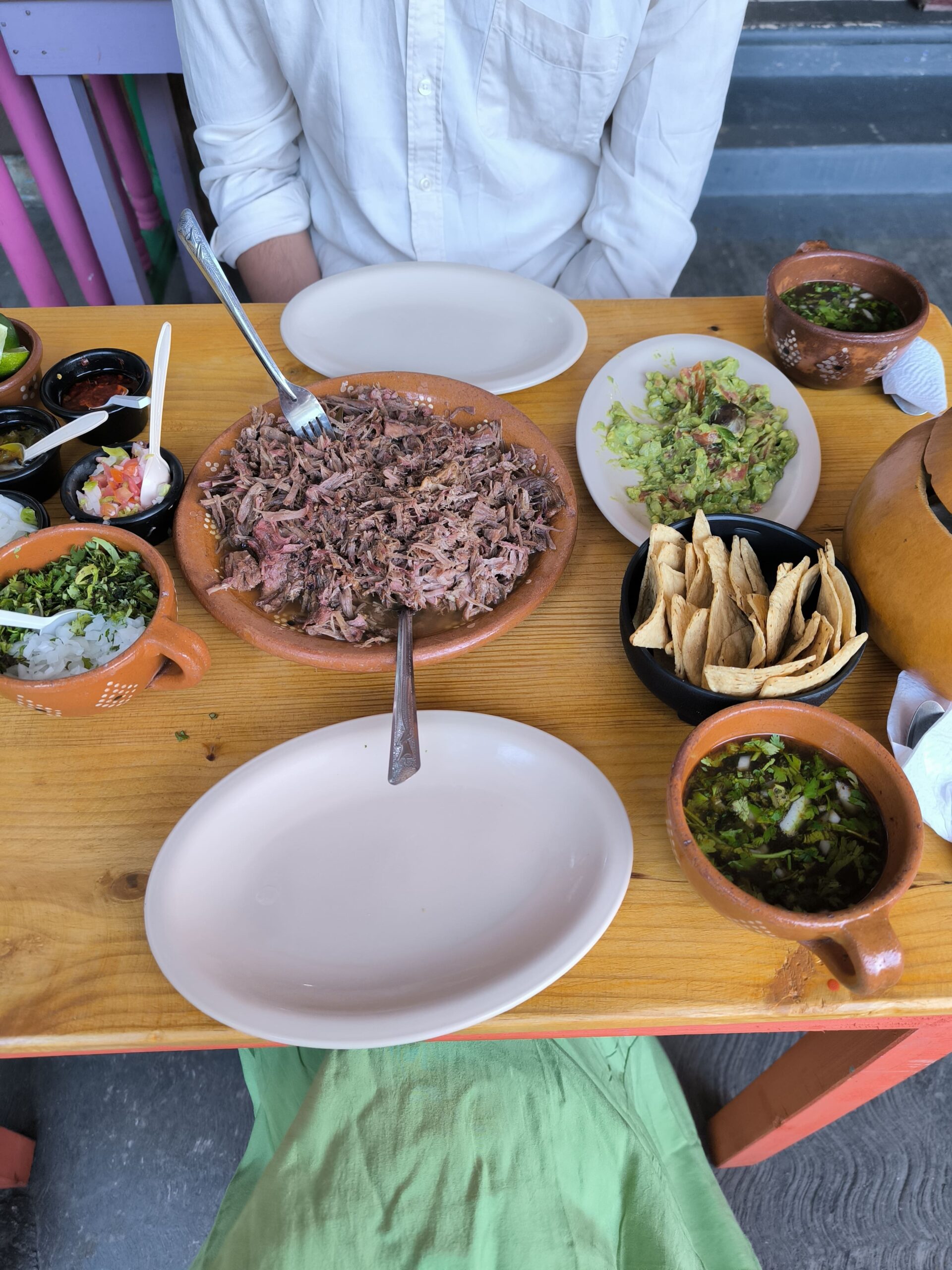 Na stole je trhané hovädzie mäso, guacamole, tortillas a mexická polievka.