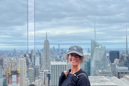 Dievča s batohom stojí pred panoramatickým výhľadom na New York.