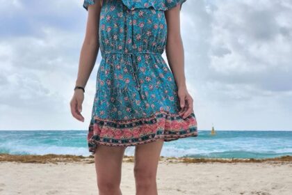 Dievča v šatách kráča po pláži.