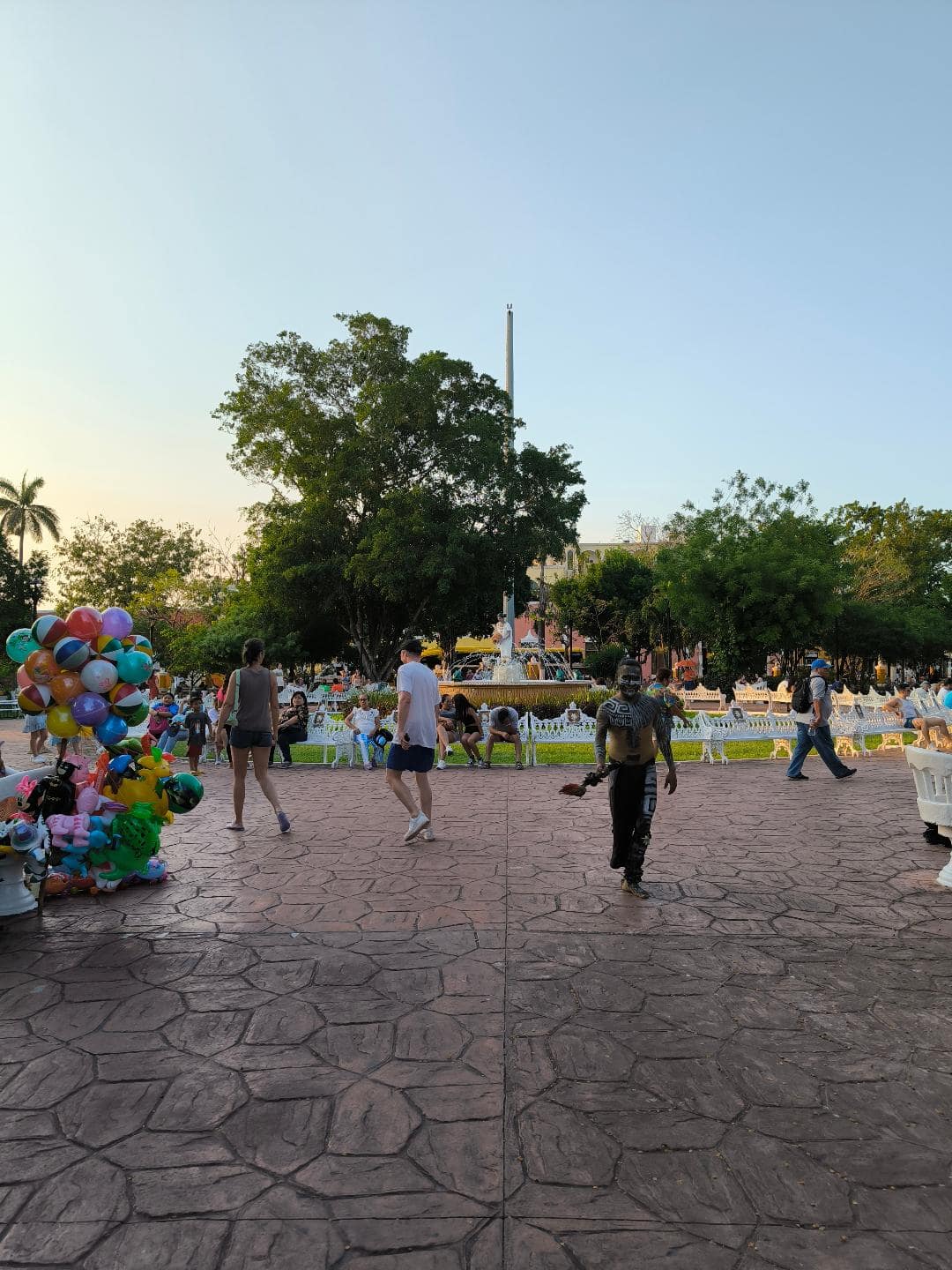 Námestia, uprostred ktorého je zelený park. Prechádza sa po ňom chlap prezlečený za pôvodného mayského človeka.