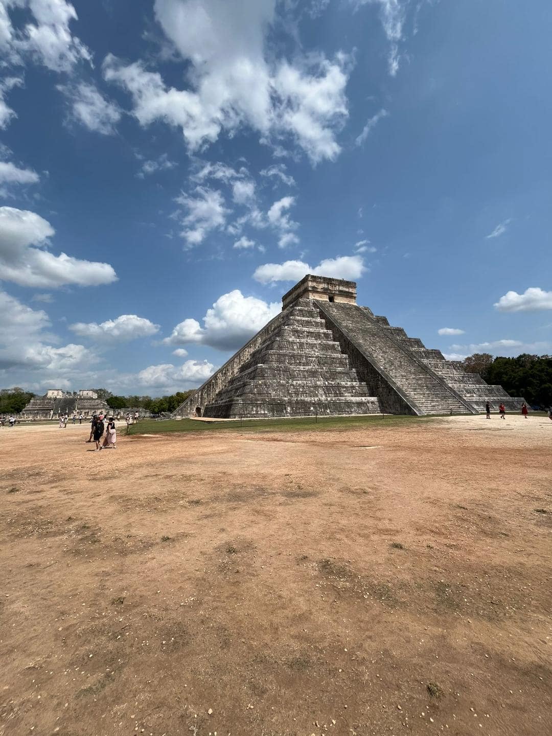 Vysoká pyramída uprostred poľa. Okolo nej nič nie je a na oblohe sú biele mraky.