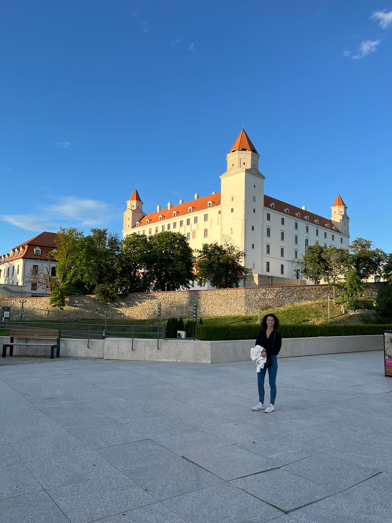 Dievča stojí pred bielym hradom s červenými vežami.