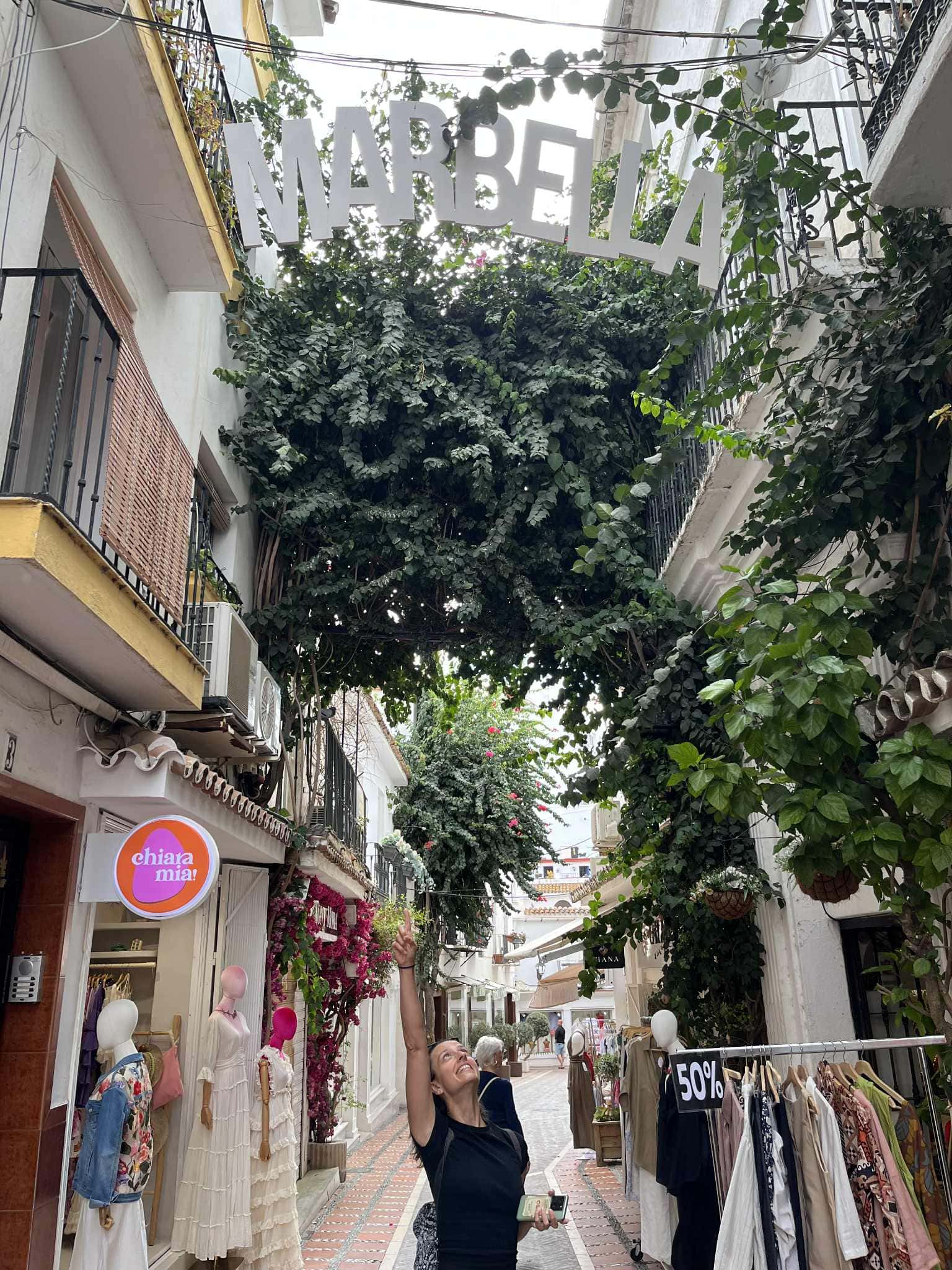 Dievča v čiernom tričku stojí pod veľkým nápisom Marbella.